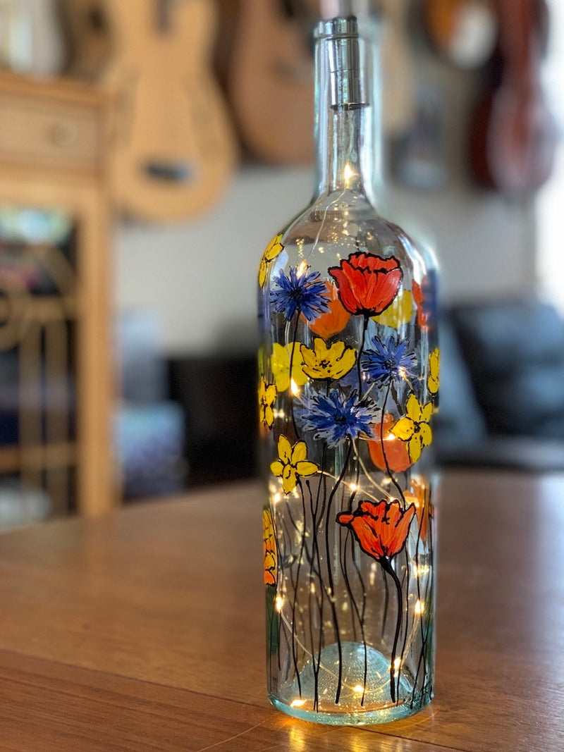 Monet is known to have this garden of blue, red and yellow flowers. Painted on a recycled bottle with acrylic paint. The bottle is lit with fairy lights from within.